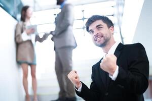 affaires gens et Bureau concept. content souriant homme d'affaire dans foncé costume. portrait de souriant milieu adulte homme d'affaire permanent à entreprise bureau. homme d'affaire souriant avec bras franchi dans bureau. photo