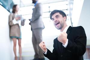 affaires gens et Bureau concept. content souriant homme d'affaire dans foncé costume. portrait de souriant milieu adulte homme d'affaire permanent à entreprise bureau. homme d'affaire souriant avec bras franchi dans bureau. photo