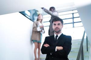 affaires gens et Bureau concept. content souriant homme d'affaire dans foncé costume. portrait de souriant milieu adulte homme d'affaire permanent à entreprise bureau. homme d'affaire souriant avec bras franchi dans bureau. photo