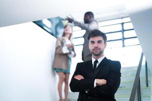 affaires gens et Bureau concept. content souriant homme d'affaire dans foncé costume. portrait de souriant milieu adulte homme d'affaire permanent à entreprise bureau. homme d'affaire souriant avec bras franchi dans bureau. photo