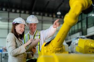 usine ingénieurs inspecter sur machine avec intelligent tablette. ouvrier travaux à lourd machine robot bras. le soudage machine avec une éloigné système dans un industriel usine. artificiel intelligence concept. photo