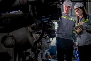 usine ingénieur femme inspecter sur machine avec intelligent tablette. ouvrier travaux à machine robot bras. le soudage machine avec une éloigné système dans un industriel usine. artificiel intelligence concept. photo