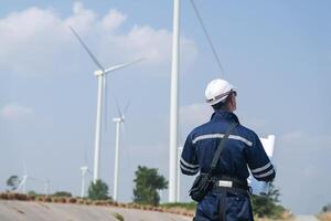 ingénieurs travail dans travail sur le terrain Extérieur. ouvriers en marchant et inspecter construction et machine autour projet placer. vent turbine électrique de nettoyer Ressource énergique et environnement durable. photo