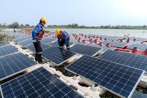 Masculin ouvriers réparation flottant solaire panneaux sur l'eau lac. ingénieurs construction sur site flottant solaire panneaux à Soleil lumière. nettoyer énergie pour futur vie. industriel renouvelable énergie de vert pouvoir. photo