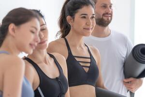 groupe de content sportif femmes et gars portant corps élégant tenue de sport en portant personnel les tapis penché sur une blanc Contexte. attendre pour yoga classe ou corps poids classe. en bonne santé mode de vie et bien-être photo