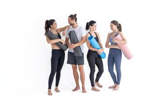 groupe de content sportif les filles et gars portant corps élégant tenue de sport en portant personnel les tapis penché sur une blanc Contexte. attendre pour yoga classe ou corps poids classe. en bonne santé mode de vie et bien-être photo