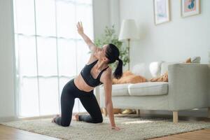 proche en haut femmes sur de soi formation yoga. athlétique femmes dans tenue de sport Faire aptitude élongation des exercices à Accueil dans le vivant chambre. sport et des loisirs concept. yoga prof est portion fille. photo