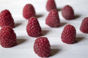 mûr framboises sur une blanc en bois Contexte. photo