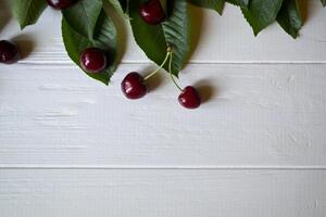le branche avec mûr cerises sur une blanc en bois Contexte. photo