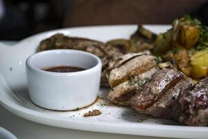 le Viande et frit patates avec sauce sur le blanc plaque. photo