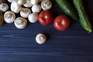 des légumes sur une tableau. champignons, tomates et concombres sur une bleu rustique Contexte. photo