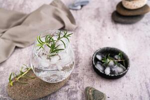 verre avec carbonaté alcoolique boisson avec Romarin et la glace dans verre sur table photo