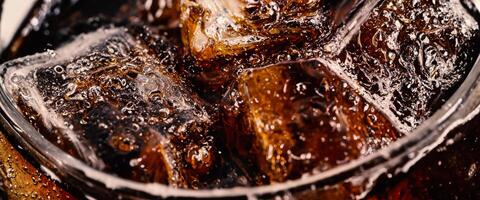 Cola avec glace. proche en haut de le la glace cubes dans Cola l'eau. texture de carbonate boisson avec bulles dans verre. Cola un soda et la glace éclabousser pétillant ou flottant en haut à Haut de surface. du froid boisson Contexte. photo