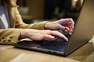femelle main dactylographie sur portable clavier dans café photo