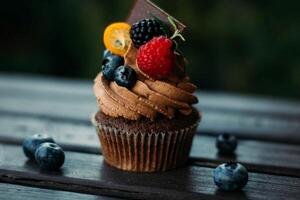 Chocolat petit gâteau avec baies sur une en bois table dans le jardin photo