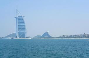 le iconique burj Al arabe des stands grand à côté de luxe en bord de mer stations balnéaires sur une clair journée dans de Dubaï paysage marin. Dubai, Émirats arabes unis - août 15, 2023 photo