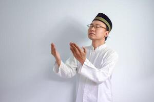 asiatique musulman homme portant des lunettes et blanc tissu Faire prier main pose pour ramadhan et eid Al fitr. isolé blanc Contexte photo