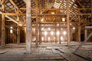 vieux Grange en bois poutres de lumière du soleil intérieur poussiéreux ferme vide photo