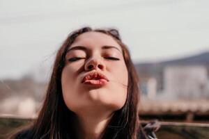 content Jeune souriant femme avec taches de rousseur en plein air portrait. doux ensoleillé couleurs. Extérieur fermer portrait de une Jeune brunette femme et à la recherche à le caméra, posant contre l'automne la nature Contexte photo