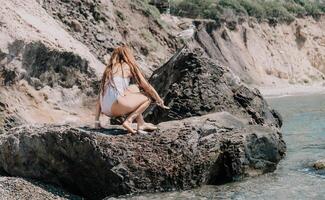 femme Voyage mer. content touristique dans blanc bikini prendre plaisir prise image en plein air pour souvenirs. femme voyageur posant sur le plage à mer entouré par volcanique montagnes, partage Voyage aventure périple photo