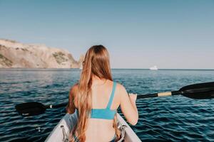 femme dans kayak retour voir. content Jeune femme avec longue cheveux flottant dans kayak sur calme mer. été vacances vacances et de bonne humeur femelle gens relaxant ayant amusement sur le bateau. photo