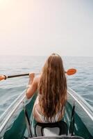 femme dans kayak retour voir. content Jeune femme avec longue cheveux flottant dans transparent kayak sur le cristal clair mer. été vacances vacances et de bonne humeur femelle gens relaxant ayant amusement sur le bateau photo