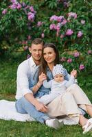 content caucasien famille avec une Jeune fils se détendre dans le parc dans printemps ou été, séance sur une couverture photo