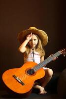 portrait de une caucasien bambin fille portant une paille chapeau et en portant le guitare photo