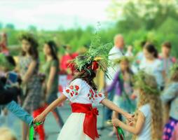 Jeune fille portant une couronne et ethnique ukrainien vêtements avec brodé rouge fleurs dansant dans une bague célébrer païen vacances de Ivan kupala photo