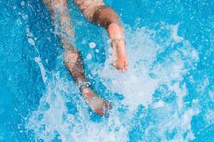 enfant éclabousser dans le cool l'eau de une bassin dans été photo