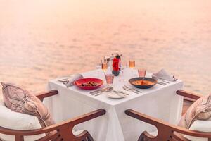 paysage marin vue en dessous de le coucher du soleil lumière avec à manger table avec infini bassin autour. romantique tranquille va-t-en pour deux, couple concept. chaises, nourriture et romance. luxe destination à manger, voyage de noces modèle photo