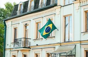 le vert drapeau de le pays de Brésil papillonne dans le vent contre le Jaune mur de le maison. photo