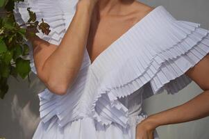 fille, femme la mariée dans une élégant blanc robe avec spectaculaire manches et encolure sur une gris Contexte. photo
