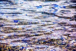 Contexte de le l'eau de Lac traunsee dans le côtier zone. coloré texture de des pierres en dessous de l'eau. photo