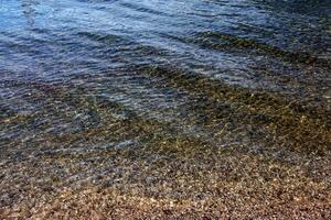 Contexte de le l'eau de Lac traunsee dans le côtier zone. coloré texture de des pierres en dessous de l'eau. photo