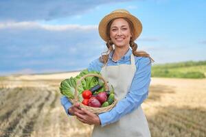 femme agriculteur paille chapeau tablier permanent les terres agricoles souriant femelle agronome spécialiste agriculture secteur agroalimentaire content positif caucasien ouvrier agricole champ photo