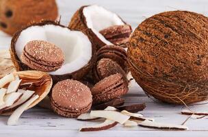 noix de coco macarons avec Chocolat et noix de coco flocons sur une table avec une noix de coco dans le Contexte photo