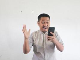 asiatique homme en portant le sien mobile téléphone avec sérieux expression photo