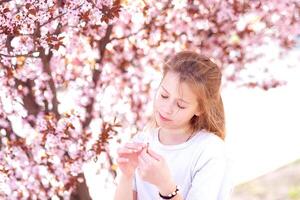 Jeune fille parmi magnifique Cerise fleurs dans plein Floraison photo