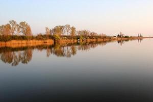 Lac maison dans l'automne reflétant dans tranquille rivière photo