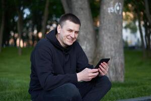 homme en train de lire électronique livre Beau gars lis e-book tablette séance Publique parc été journée caucasien Masculin en portant ebook dans main à la recherche dispositif écran photo