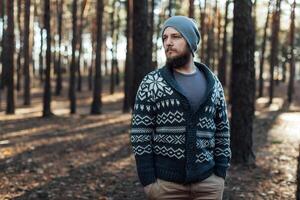 une Jeune homme avec une barbe des promenades dans une pin forêt. portrait de une brutal barbu homme l'automne forêt photo