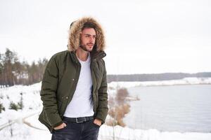 attrayant barbu homme permanent en plein air dans hiver saison forêt. photo