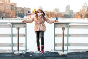 magnifique charmant Jeune adulte femme brunet cheveux chaud hiver vestes des stands près la glace patin patinoire Contexte ville carré. Noël ambiance mode de vie photo