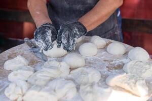 chef dans noir gants coupes brut pâte dans pièces faire Pizza galettes pain. photo