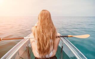 femme dans kayak retour voir. content Jeune femme avec longue cheveux flottant dans transparent kayak sur le cristal clair mer. été vacances vacances et de bonne humeur femelle gens relaxant ayant amusement sur le bateau photo