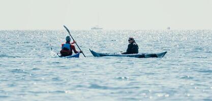 homme femme mer kayak. content gratuit homme et femme dans kayak sur océan, pagayer avec en bois rame. calme mer l'eau et horizon dans Contexte. actif mode de vie à mer. été vacances. photo