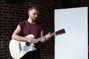 homme avec acoustique guitare permanent près tableau blanc la musique école concept photo