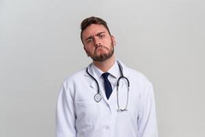 Jeune Beau moderne médecin dans une blanc médical robe des stands dans le studio sur une blanc Contexte. étudiant stagiaire de une médical université. photo