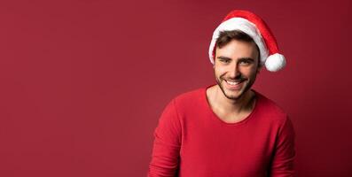 Jeune Beau caucasien gars dans rouge chandail et Père Noël Chapeaux des stands sur rouge Contexte dans studio et les dents souriant photo